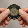 Trinity Wish Coin מוחזק בידיים, כששני האגודלים נוגעים במגעים הזהובים שלו